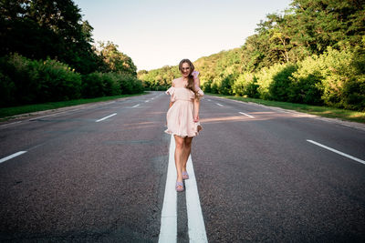 Portrait of woman standing on road against trees