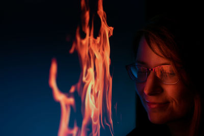 Close-up of woman with fire against black background