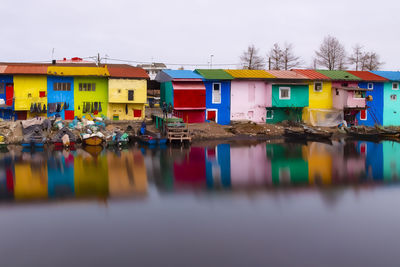 Multi colored houses by lake against sky