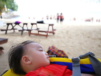 Close-up of girl sleeping at beach against sky