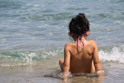 Rear view of shirtless woman in sea