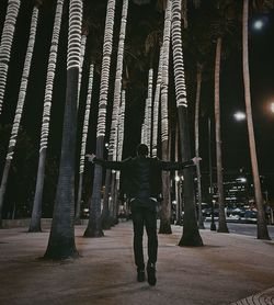 Rear view of man walking on footpath at night