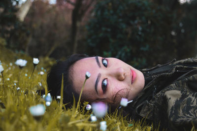 Portrait of young woman lying on field