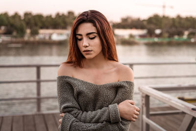 Close-up of young woman standing on pier against river