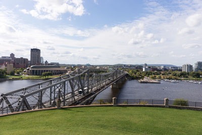 Bridge over river in city against sky