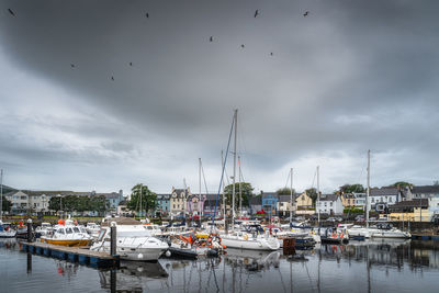 Boats moored in harbor against buildings in city