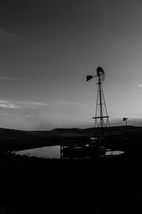 Silhouette of cranes against sky at sunset