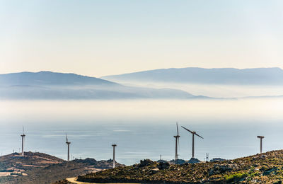 Several wind generators with gray clouds near the sea at the coast of the island of evoia, greece.