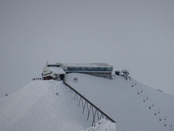 Windmill on snow covered mountain against sky