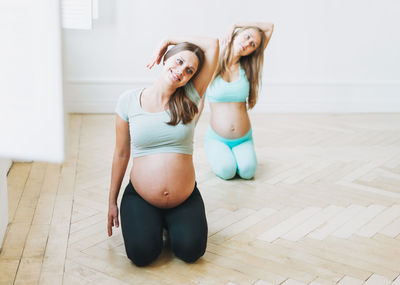 Full length of pregnant women exercising at yoga studio