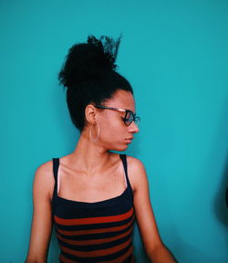 Young woman looking away against blue wall