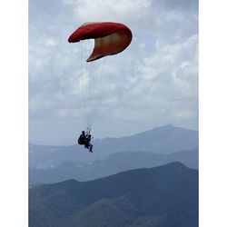Person paragliding over mountain landscape