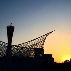 Low angle view of silhouette cranes against sky at sunset