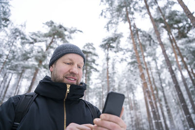 Man using smart phone in winter forest