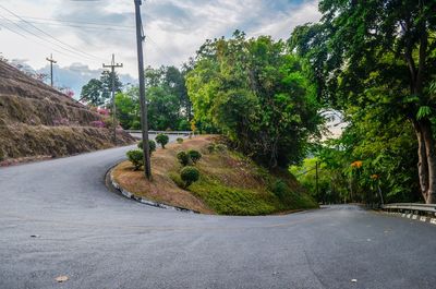 Road amidst trees in city against sky