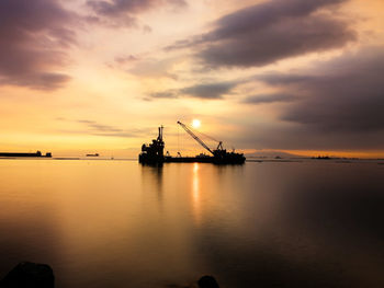 Silhouette ship in sea against sky during sunset