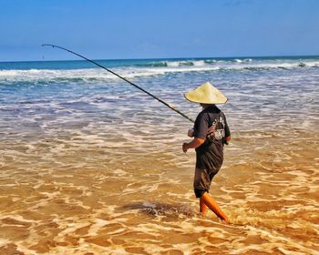 Full length rear view of man at beach against sky