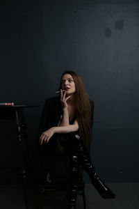 Portrait of young woman standing against wall