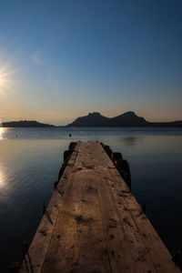 Pier over sea against sky during sunset