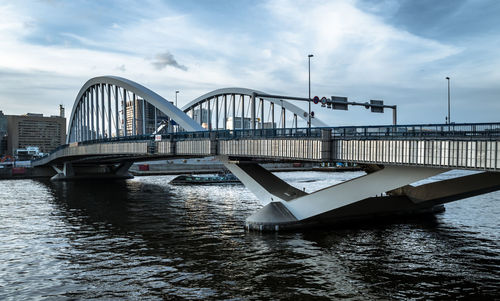 Bridge over river in city against sky