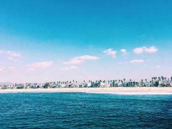 Scenic view of sea and buildings against blue sky