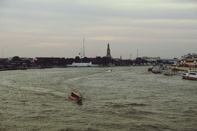 Boats in river with city in background