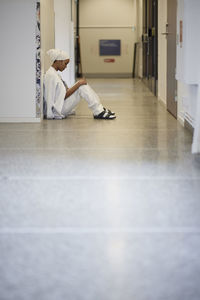 Female doctor sitting on hospital corridor floor