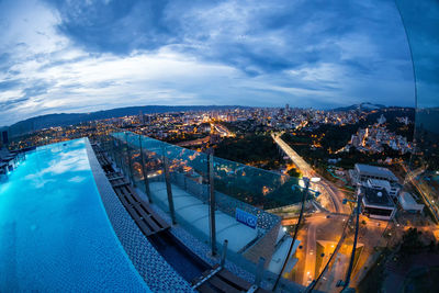 High angle view of illuminated cityscape against blue sky