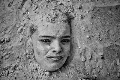 Close-up portrait of boy buried in sand