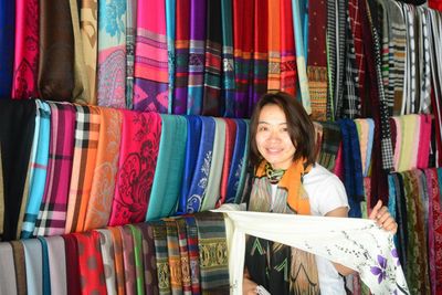 Portrait of smiling mid adult woman buying scarfs at market