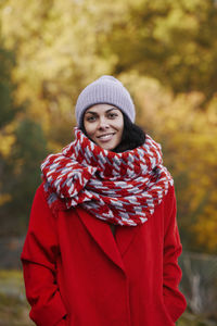 Portrait of smiling young woman standing against trees