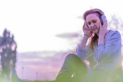 Young woman looking away against sky