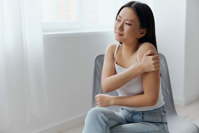 Young woman sitting on bed at home