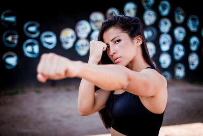 Portrait of young woman with arms raised standing outdoors