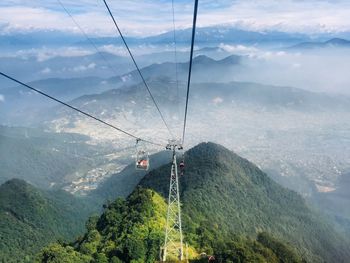 Overhead cable car over mountains against sky