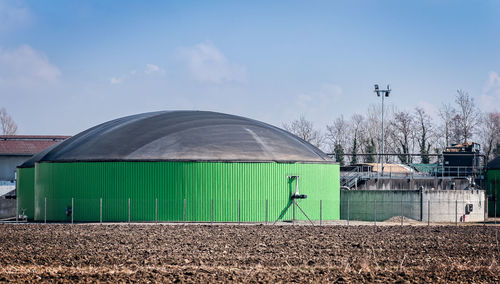 Row of barn on field against sky