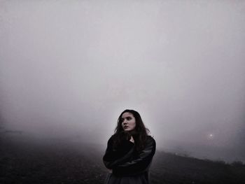 Young woman in fog against sky at night