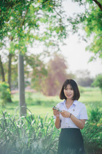 Portrait of woman standing against trees