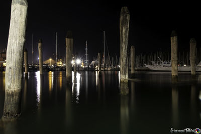 Sailboats moored in sea against sky at night