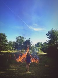 Rear view of woman standing on field against sky