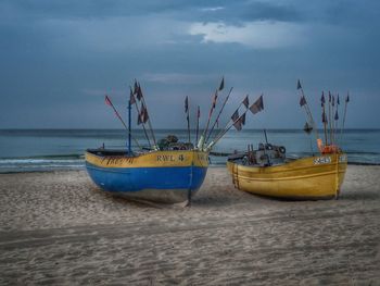 Sailboats moored on beach against sky