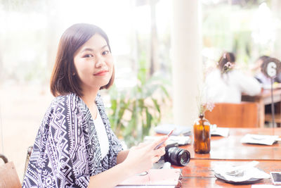 Portrait of woman using mobile phone on table