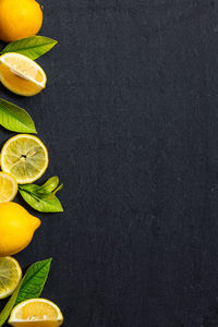 Fresh lemons on dark stone table. ripe lemon from top view with green leaves with copy spase