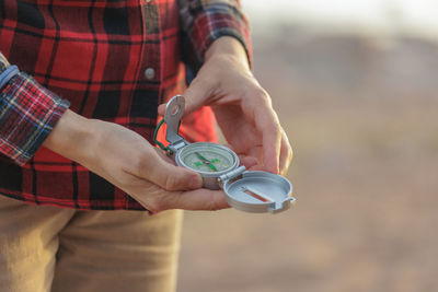 Midsection of man holding navigational compass