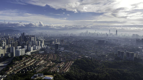 High angle view of city buildings against cloudy sky