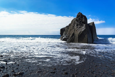 Rock formation on beach against sky