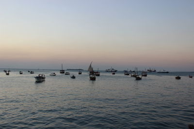 Boats anchored on sea at dusk