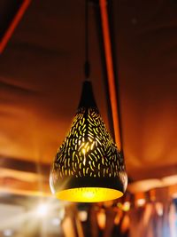 Close-up of illuminated light bulb hanging on wall