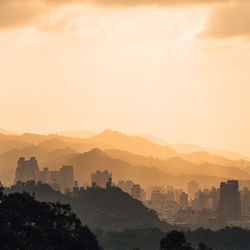 Aerial view of buildings and mountains against sky during sunset