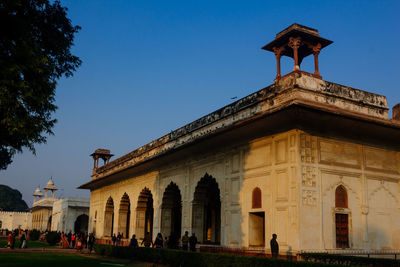 People in front of historical building against clear sky